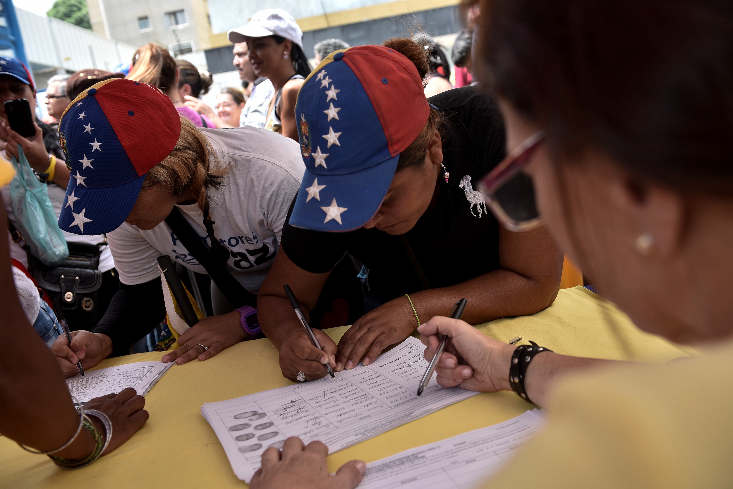 People sign for the referendum petition to revoke Nicolas Maduro's term in Caracas on April 27.
