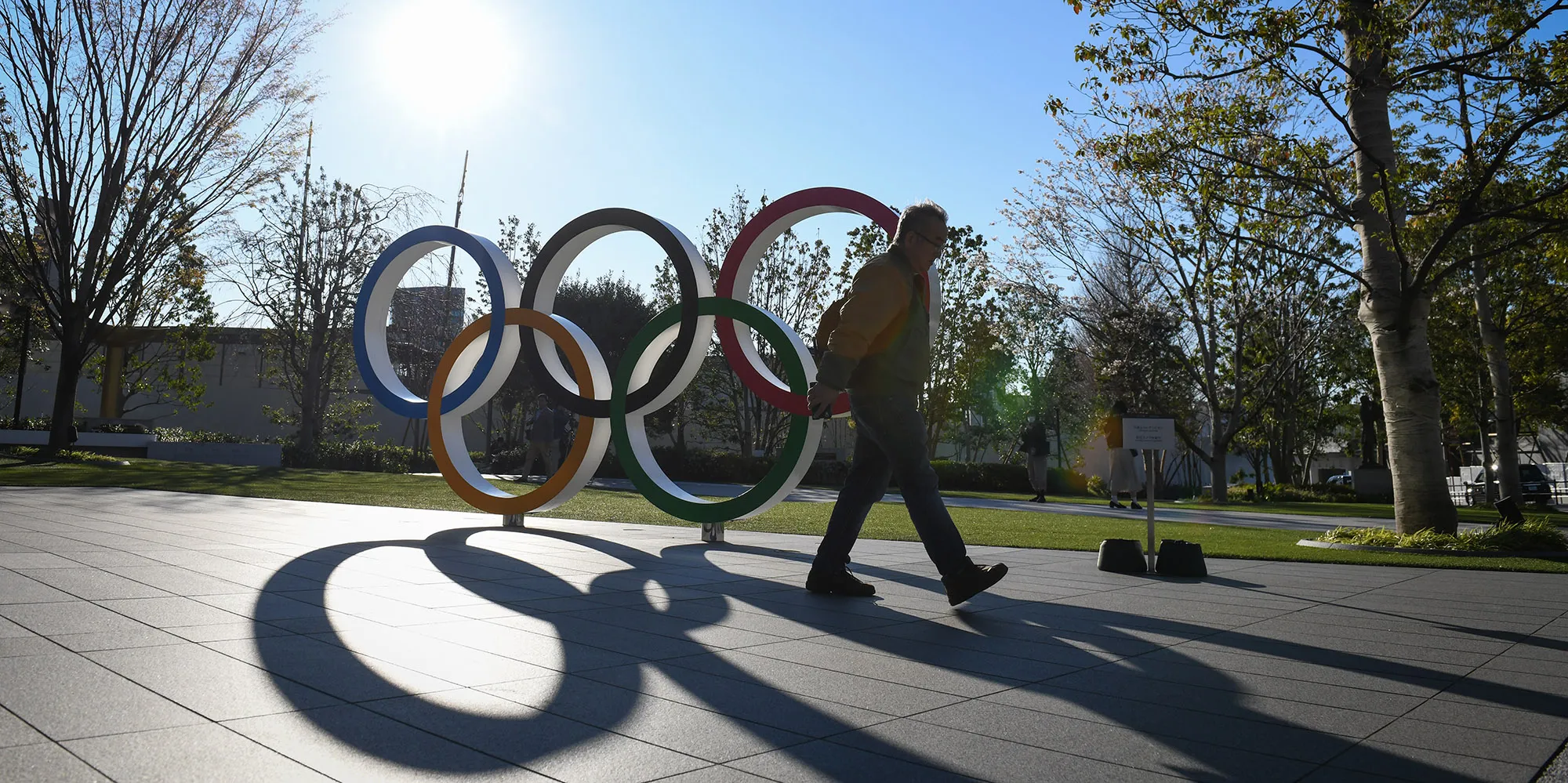 A pedestrian walks past the Olympics rings at the Japan Olympic Museum located in front of the main stadium of the upcoming Olympics in Tokyo, on&nbsp;March 24.