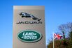 A totem displaying company logos next to a British union flag at the entrance to Tata Motors Ltd.'s Jaguar Land Rover vehicle manufacturing plant in Solihull, UK.
