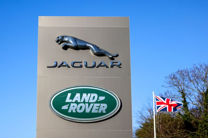 A totem displaying company logos next to a British union flag at the entrance to Tata Motors Ltd.'s Jaguar Land Rover vehicle manufacturing plant in Solihull, UK.