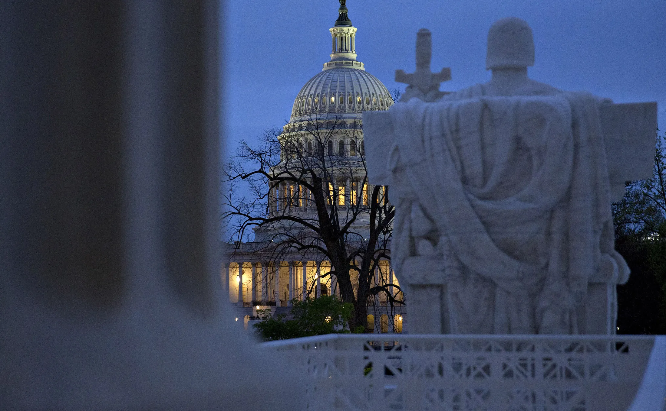 The U.S. Capitol building stands past the 'Authority of Law' statue at the U.S. Supreme Court building in Washington, D.C.

