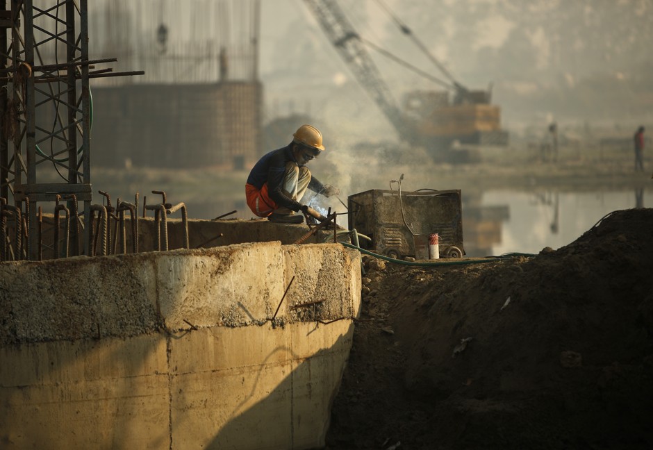 A laborer wields at the construction site of a bridge in New Delhi.