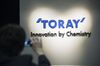 A member of the media takes a photograph of Toray Industries Inc. signage at the company's headquarters in Tokyo, Japan.