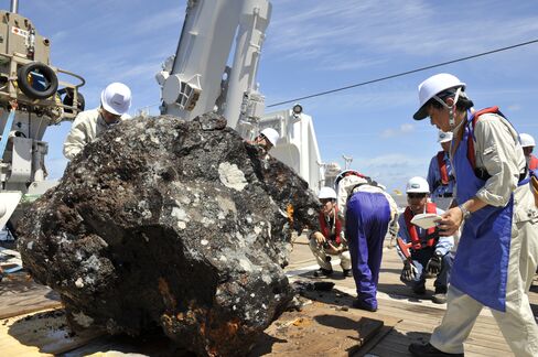 A piece of mineral is pulled aboard a vessel in a mining operation.