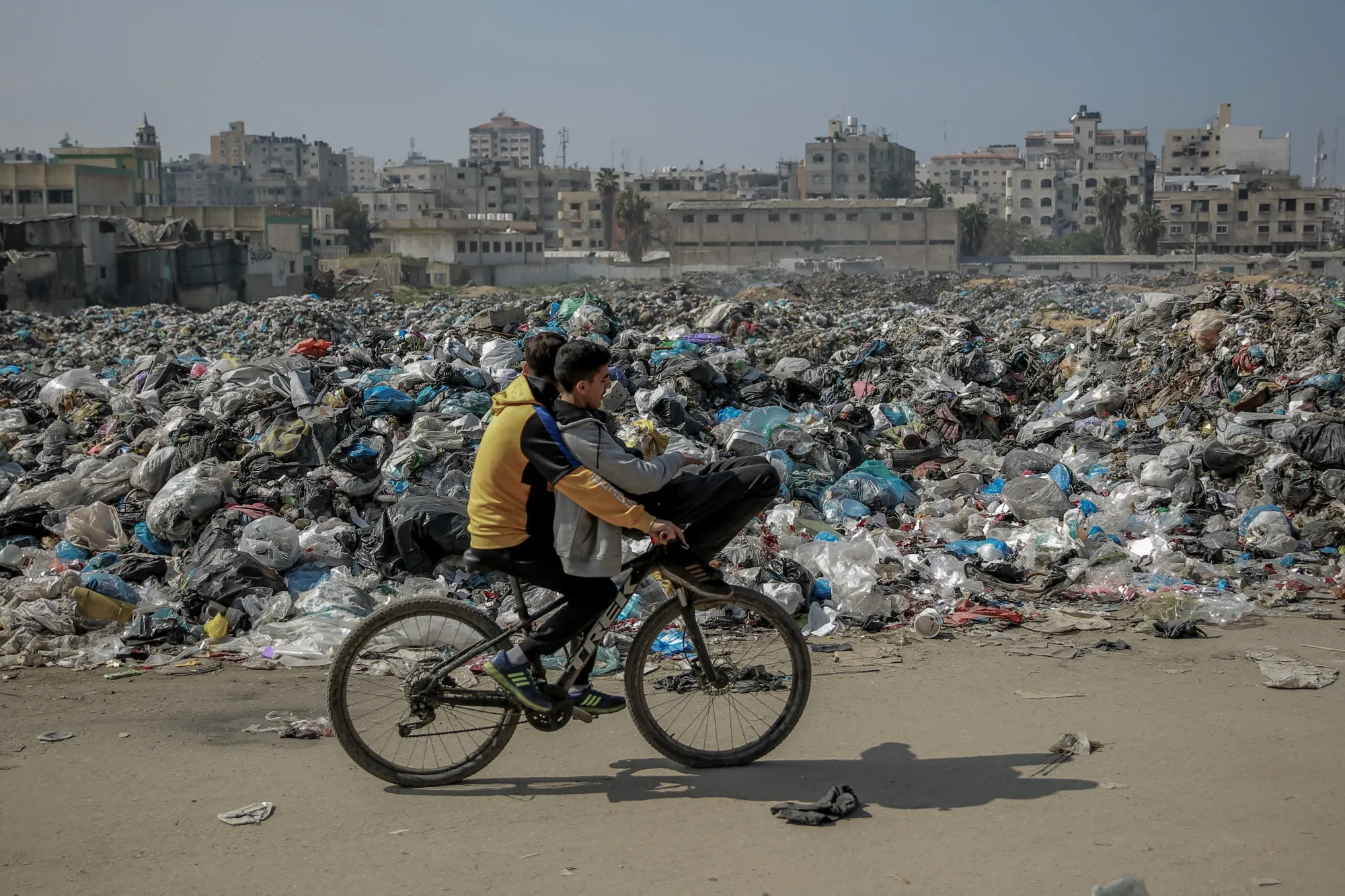 Palestinian boys pass on their bicycle a huge garbage dump along a main road in Gaza City on Feb. 24.