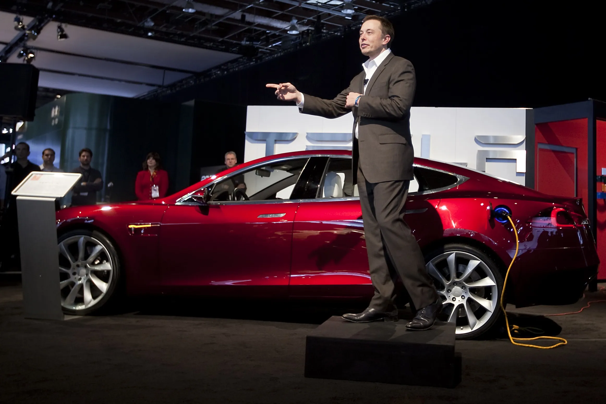 Elon Musk speaking in front of a Tesla Model S at the 2010 North American International Auto Show in Detroit.