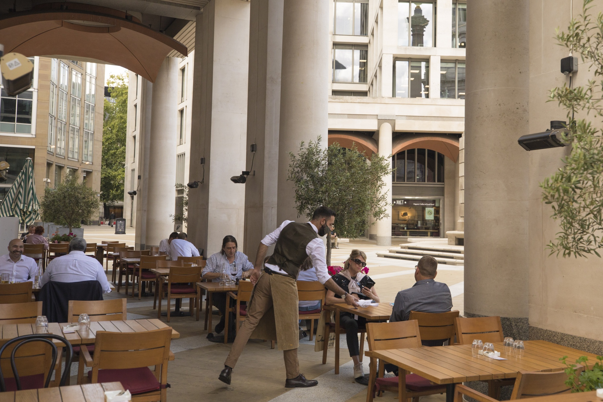A waiter serves diners outside a restaurant at The London Stock Exchange in London, U.K., on Aug. 3.
