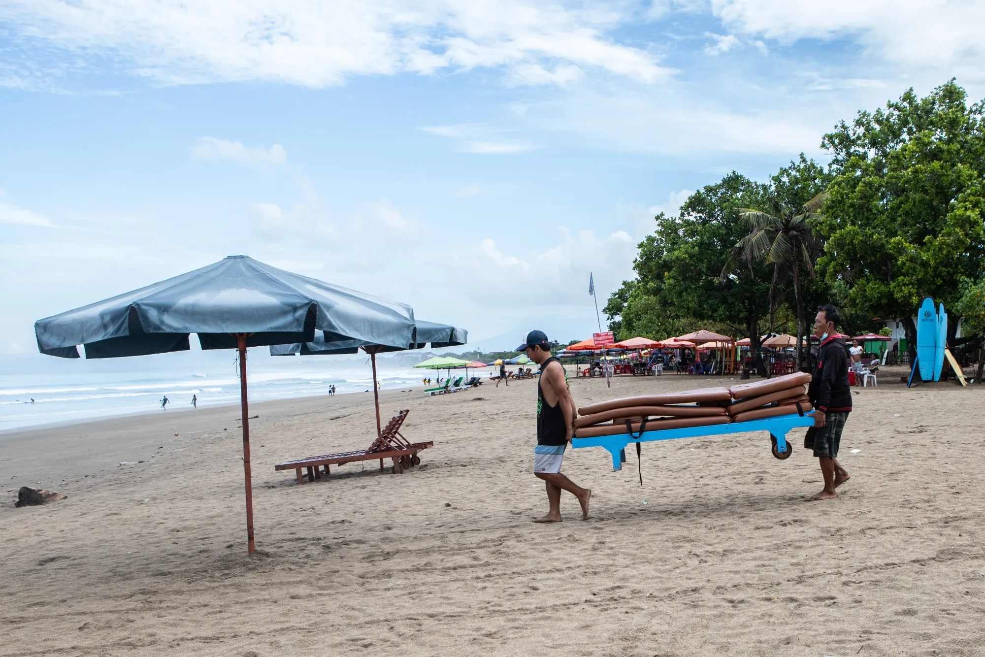 Men carry a lounge chair at the beach in the Kuta area of Bali, Indonesia.