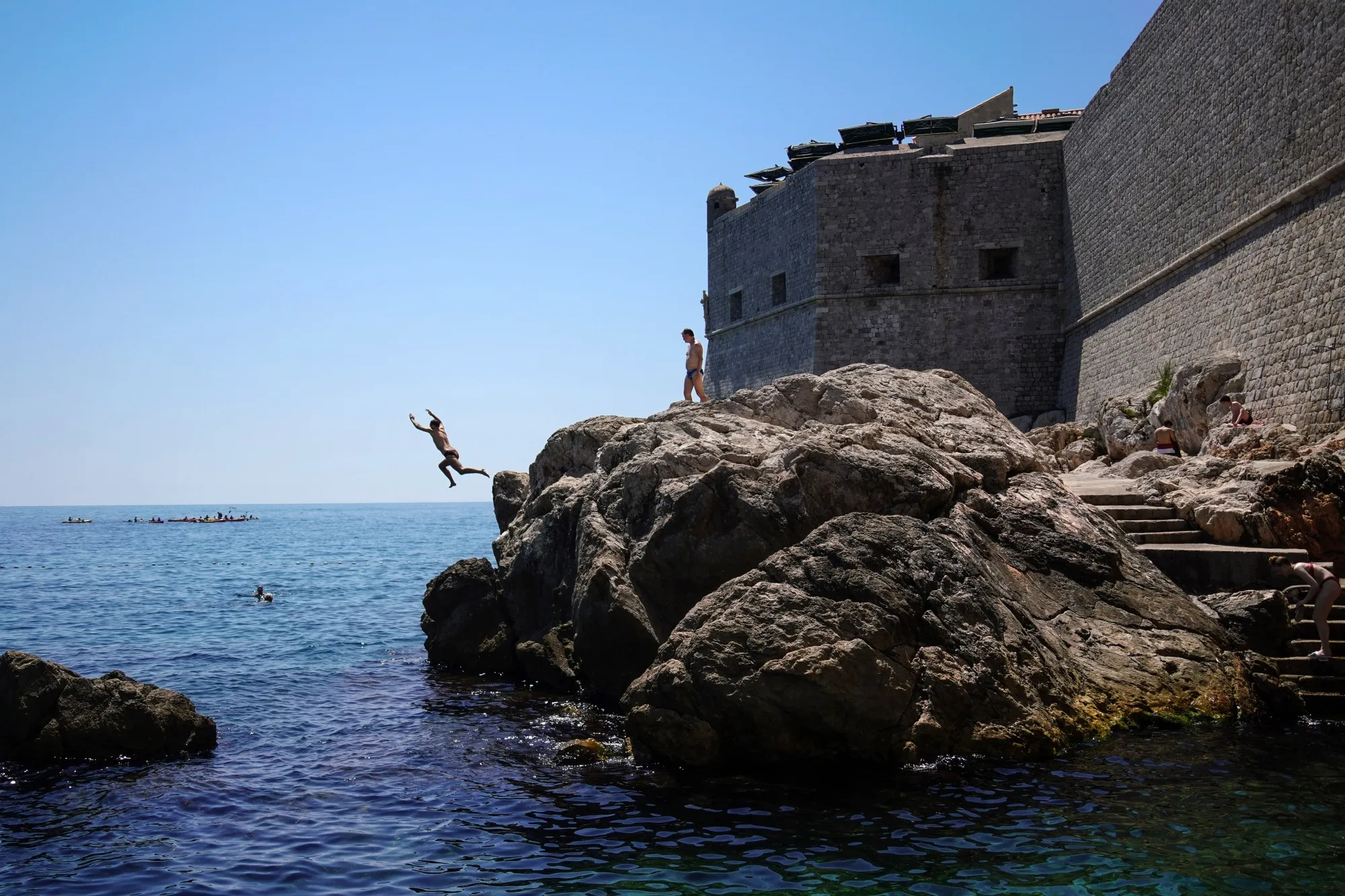 Visitors rock-jumping outside the medieval walls of the Old Town in Dubrovnik.