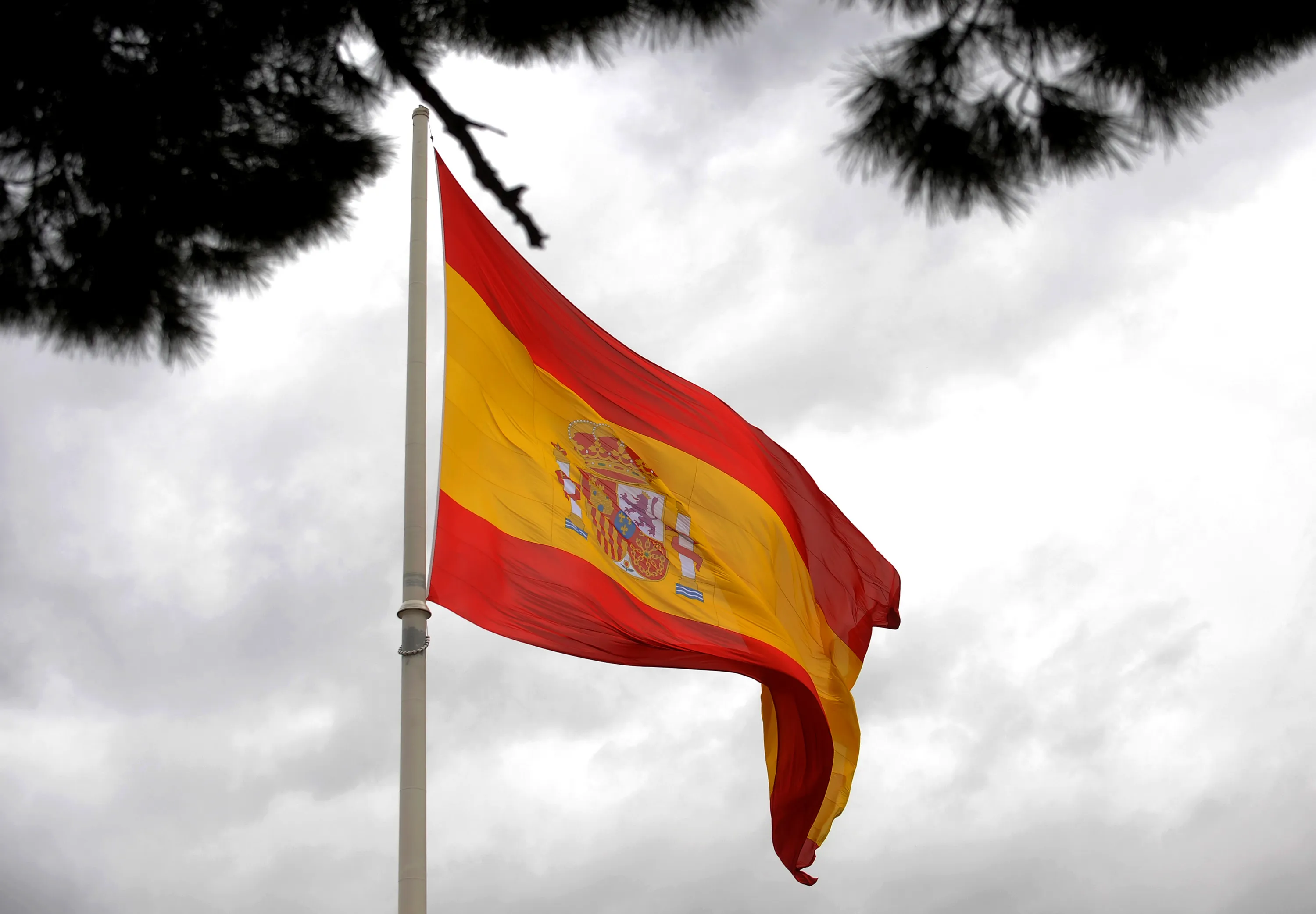The Spanish national flag is seen flying near the Plaza Colon in Madrid, Spain, on Tuesday, Feb. 14, 2012. Italian and Spanish borrowing costs plunged to the lowest in at least 11 months at debt sales today as investors ignored downgrades by Moody's Investors Service.