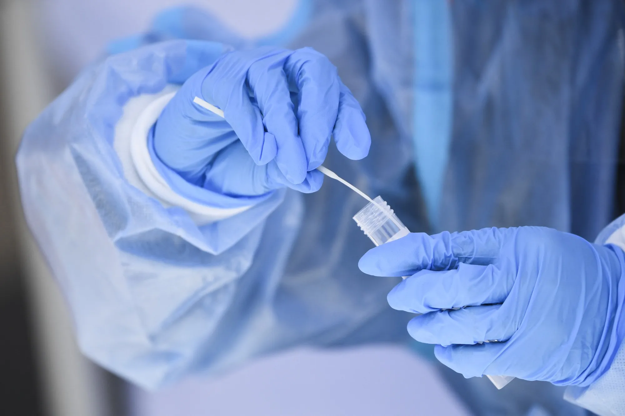 A healthcare worker places a test swab into solution for a PCR Covid-19 test.