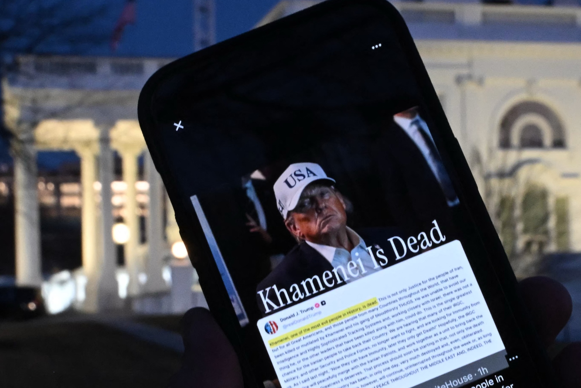 This illustration shows a person holding a smartphone displaying a Truth Social post by US President Donald Trump announcing the death of Iran's Supreme Leader Ayatollah Ali Khamenei, re-posted by the White House X account and featuring a photo of the president, near the White House in Washington, DC, on February 28, 2026. The White House on February 28 released a photo of US President Donald Trump and a handful of his top advisors monitoring the progress of joint US-Israeli air strikes on Iran. Trump has announced that Ayatollah Ali Khamenei was killed in the attacks, but there is no confirmation from Tehran. (Photo by ANDREW CABALLERO-REYNOLDS / AFP via Getty Images)