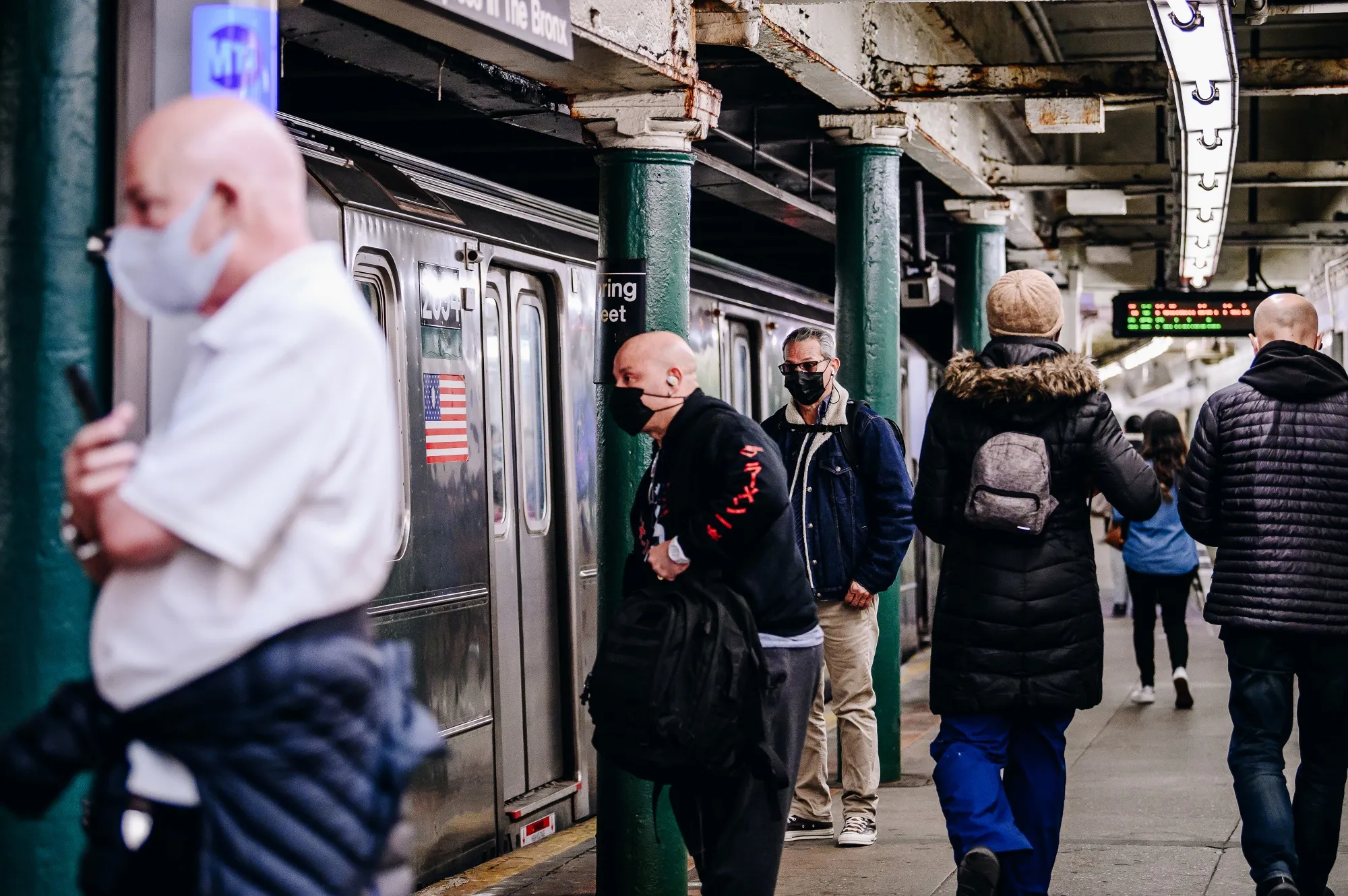 Passengers wearing protective masks wait for the 6 train at a subway station in New York.