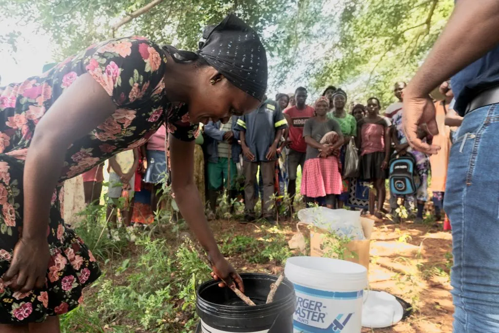 A woman explains to villagers how to purify water with chlorine, to prevent cholera outbreaks.&nbsp;