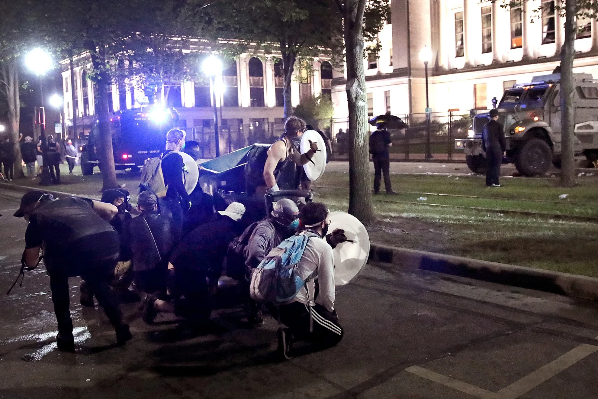 Demonstrators use shields and a dumpster for cover as they confront police in Kenosha, Wisconsin on Aug 25.