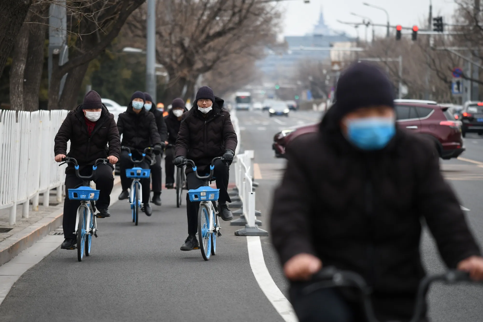 People in facemasks ride bikes in a cycle lane in Beijing on Feb. 27.