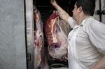 A worker hangs cuts of beef at a butcher's shop in Buenos Aires.