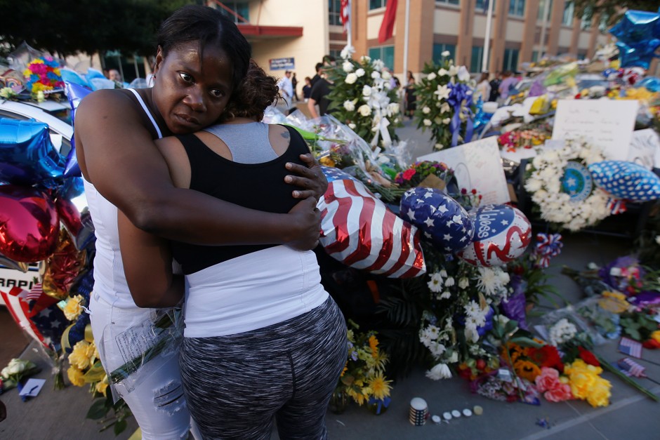 Friends support one another near a makeshift memorial at Dallas Police Headquarters following a fatal ambush on officers in downtown Dallas on July 8, 2016. 