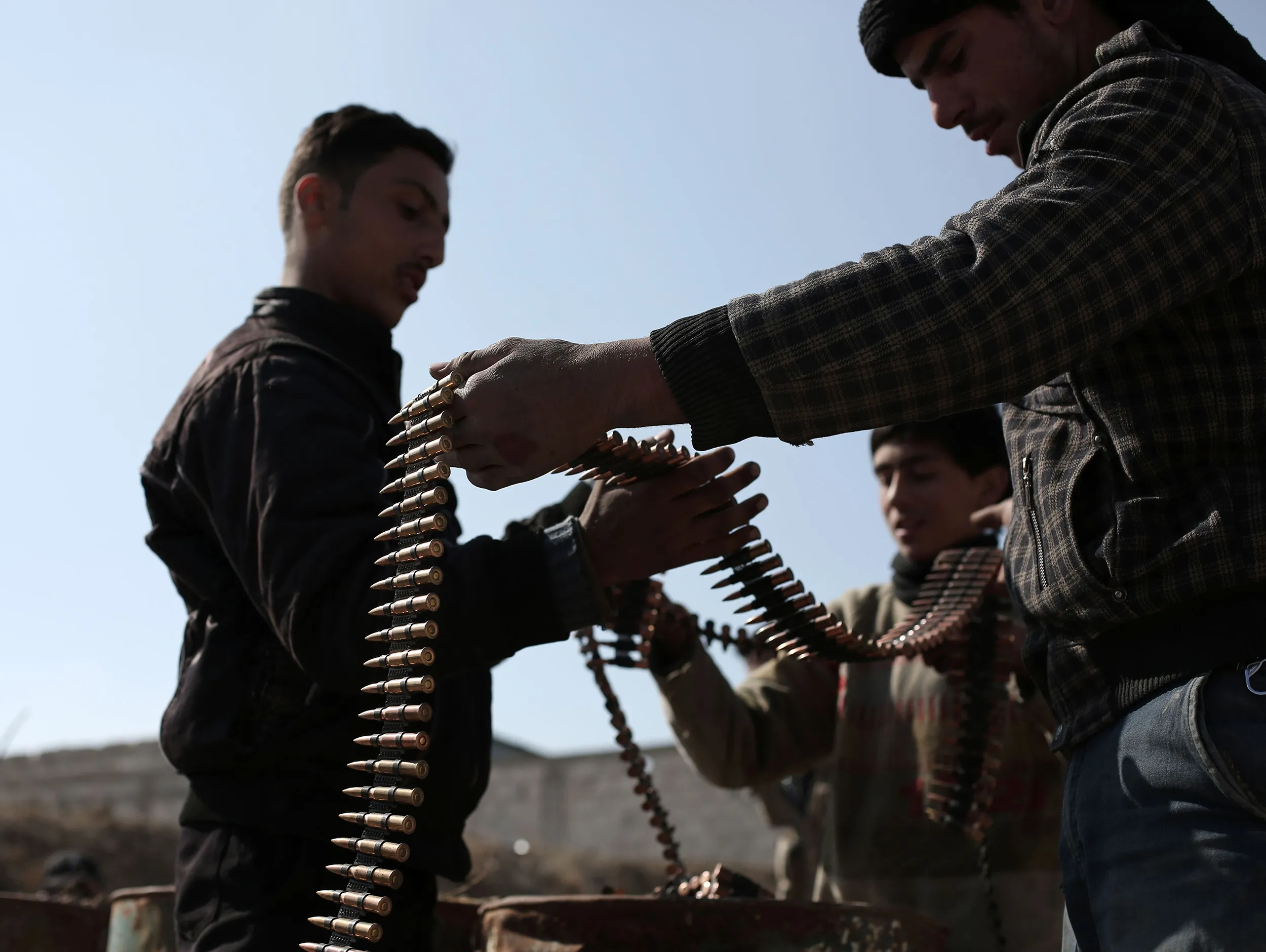 Opposition fighters belonging to Jaish al-Islam, belongong to a rebel group in Damascus check their ammunition belts.
