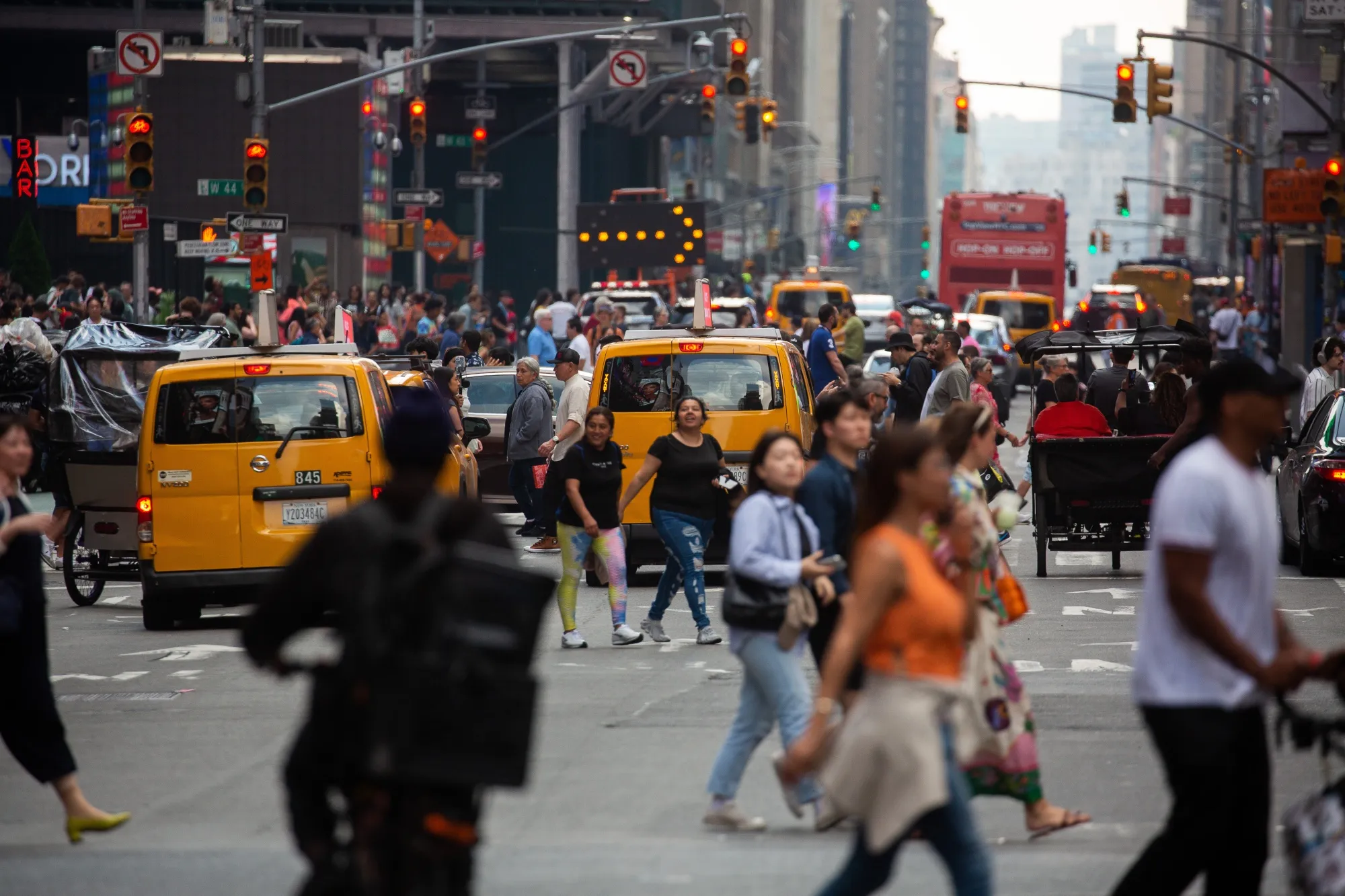 Pedestrians cross a street past traffic in the Midtown Manhattan in June.