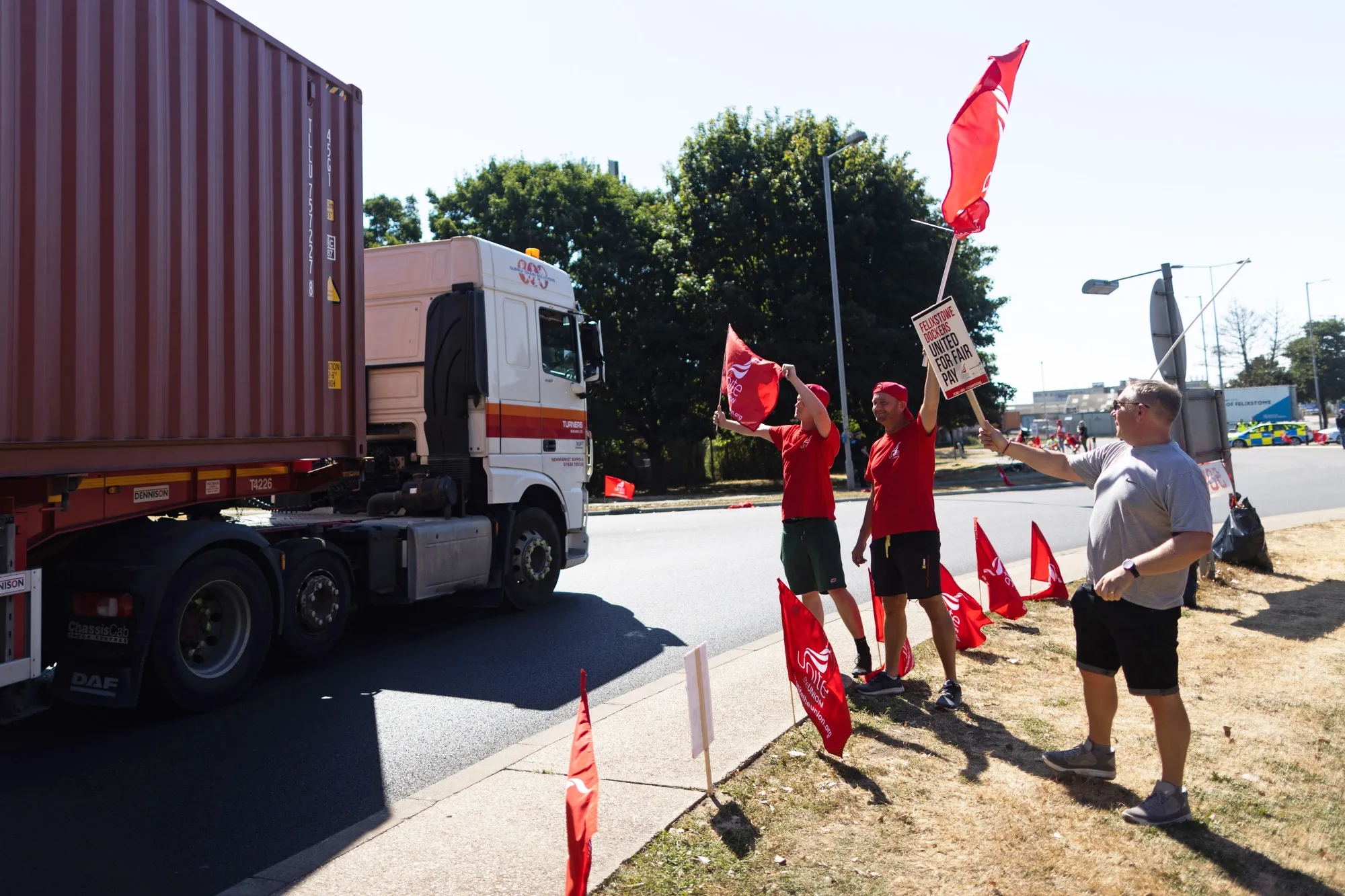 Striking Unite union members and dockworkers wave placards at a passing truck driver leaving the Port of Felixstowe in Felixstowe, UK, on&nbsp;Aug. 24.