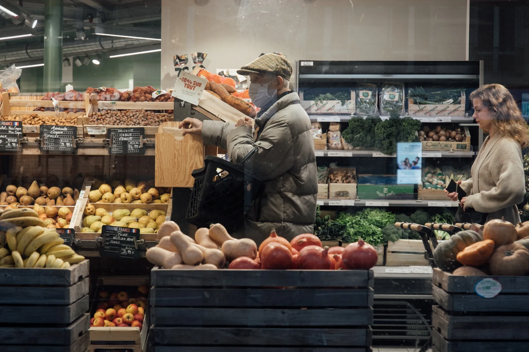 Customers shop for produce inside a grocery store in Paris, France.