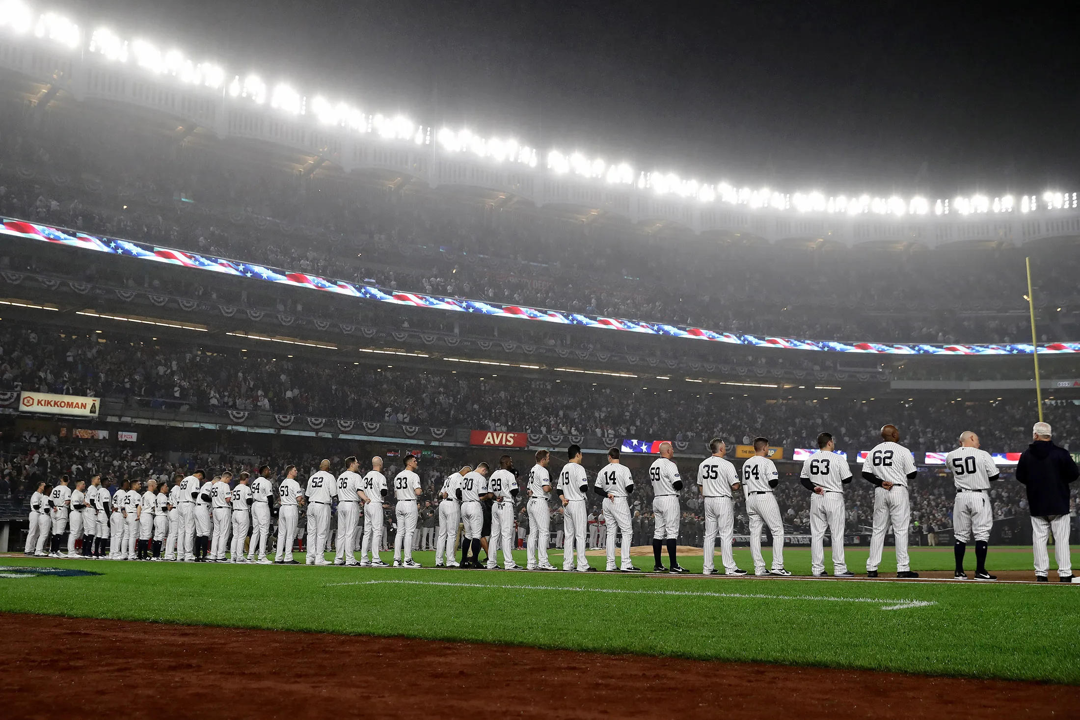 The New York Yankees stand on the first base line during the national anthem prior to Game Three of the American League Division Series against the Boston Red Sox at Yankee Stadium on October 08, 2018 in the Bronx borough of New York City. (Photo by Elsa/Getty Images)