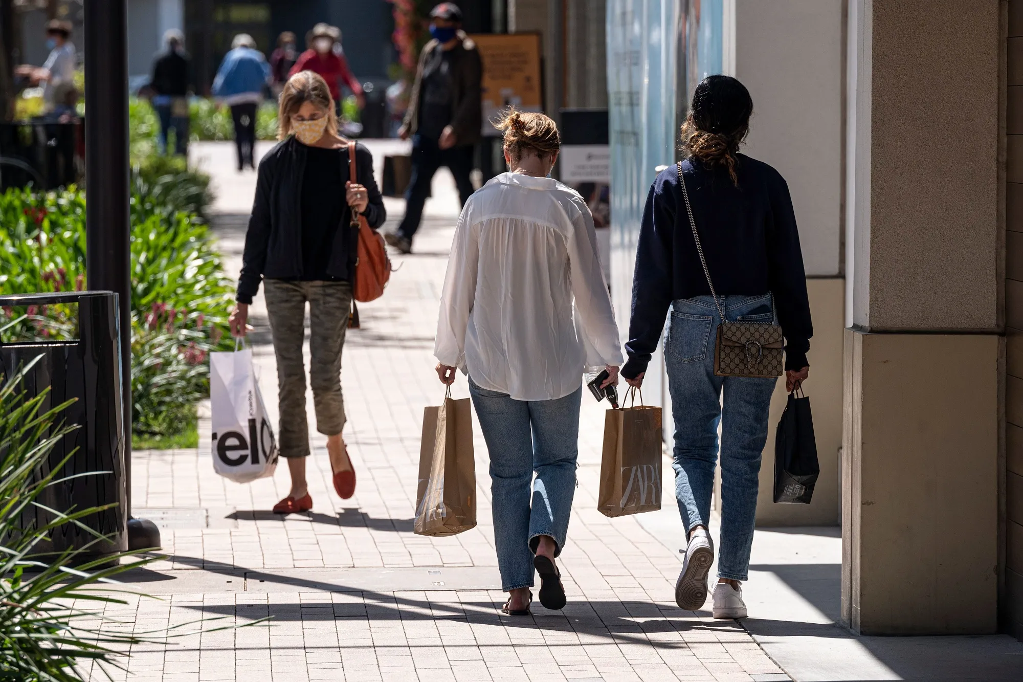 Shoppers wearing protective masks carry bags in the Broadway Plaza Shopping Center in Walnut Creek, California, U.S.,