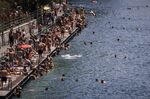 People swim in the river Limmat at Letten, in Zurich, Switzerland, Saturday, June 18, 2022. People flocked to parks and pools across Western Europe on Saturday for a bit of respite from an early heat wave that saw the mercury rise above 40 Cs (104 F) in France and Spain, and highs of 38 C (100.4 F) in Germany. (Michael Buholzer/Keystone via AP)