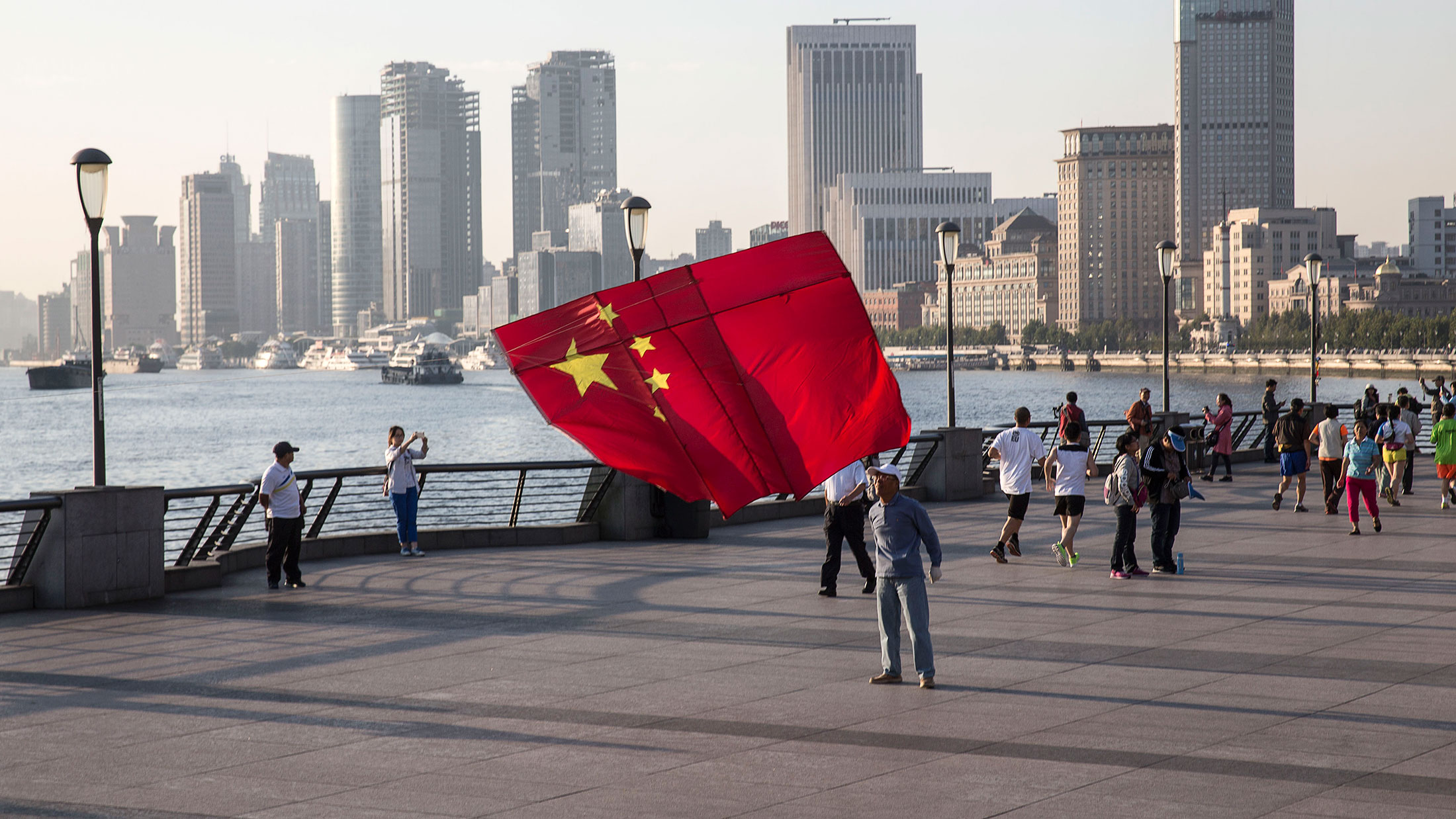 A man launches a kite in the shape of the Chinese national flag on the Bund in Shanghai. China’s policymakers are seeking ways to clean up mounting bad loans at the nation’s banks, which are at their highest levels in a decade amid slowing economic growth and government moves to curb overcapacity in manufacturing.
