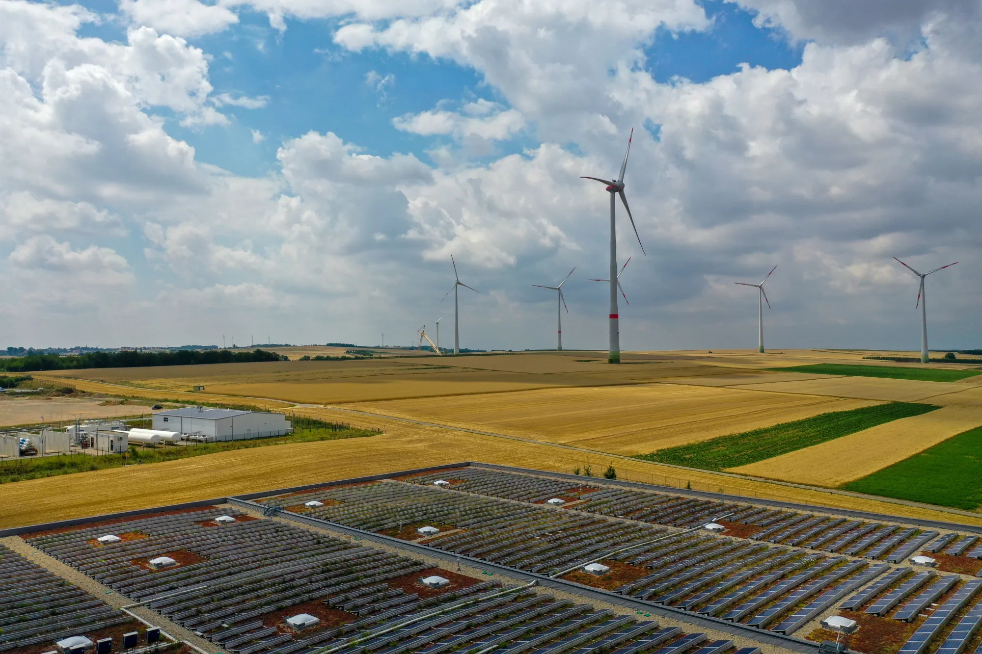 Solar panels sit on top of a warehouse near wind turbines in Mainz, Germany.