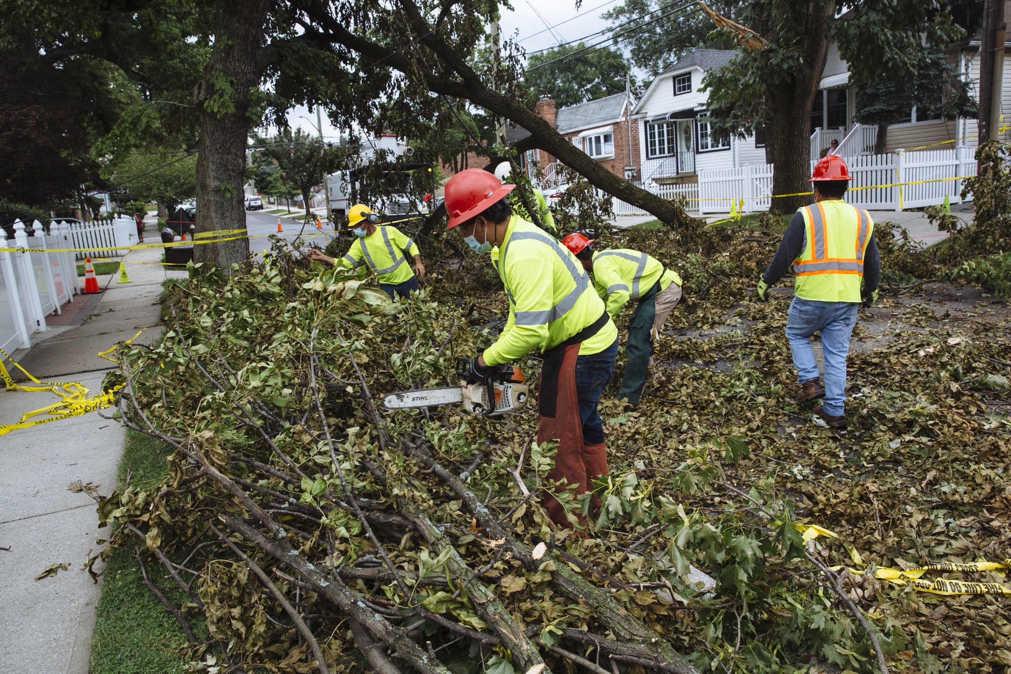 A worker uses a chainsaw to clear debris from a fallen tree in Queens, New York on Aug. 7.