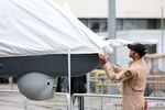 A military worker adjusts the protective cover of a General Atomics MQ-9 Predator B unmanned aircraft system drone