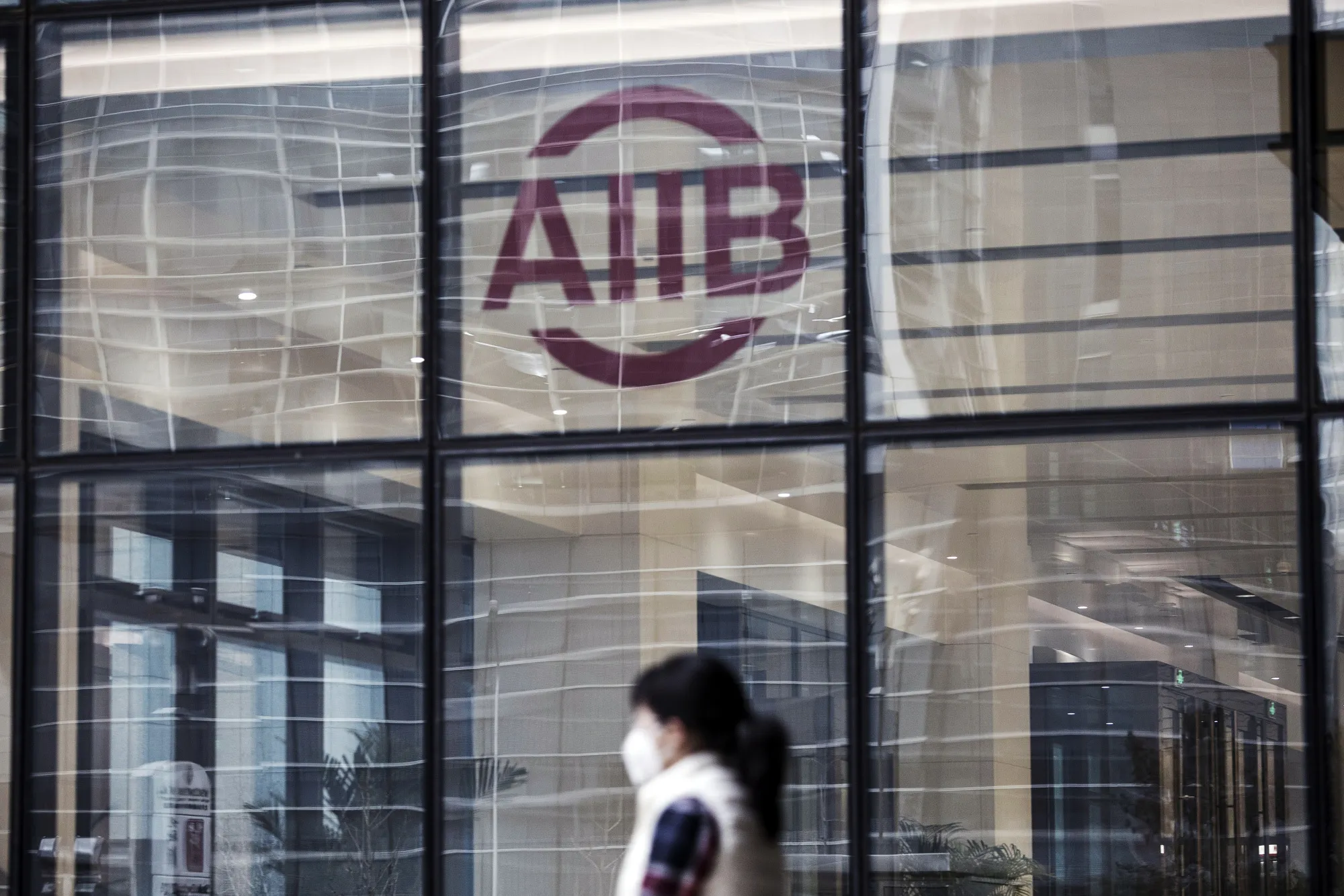 A woman passes the Asian Infrastructure Investment Bank headquarters building in Beijing.