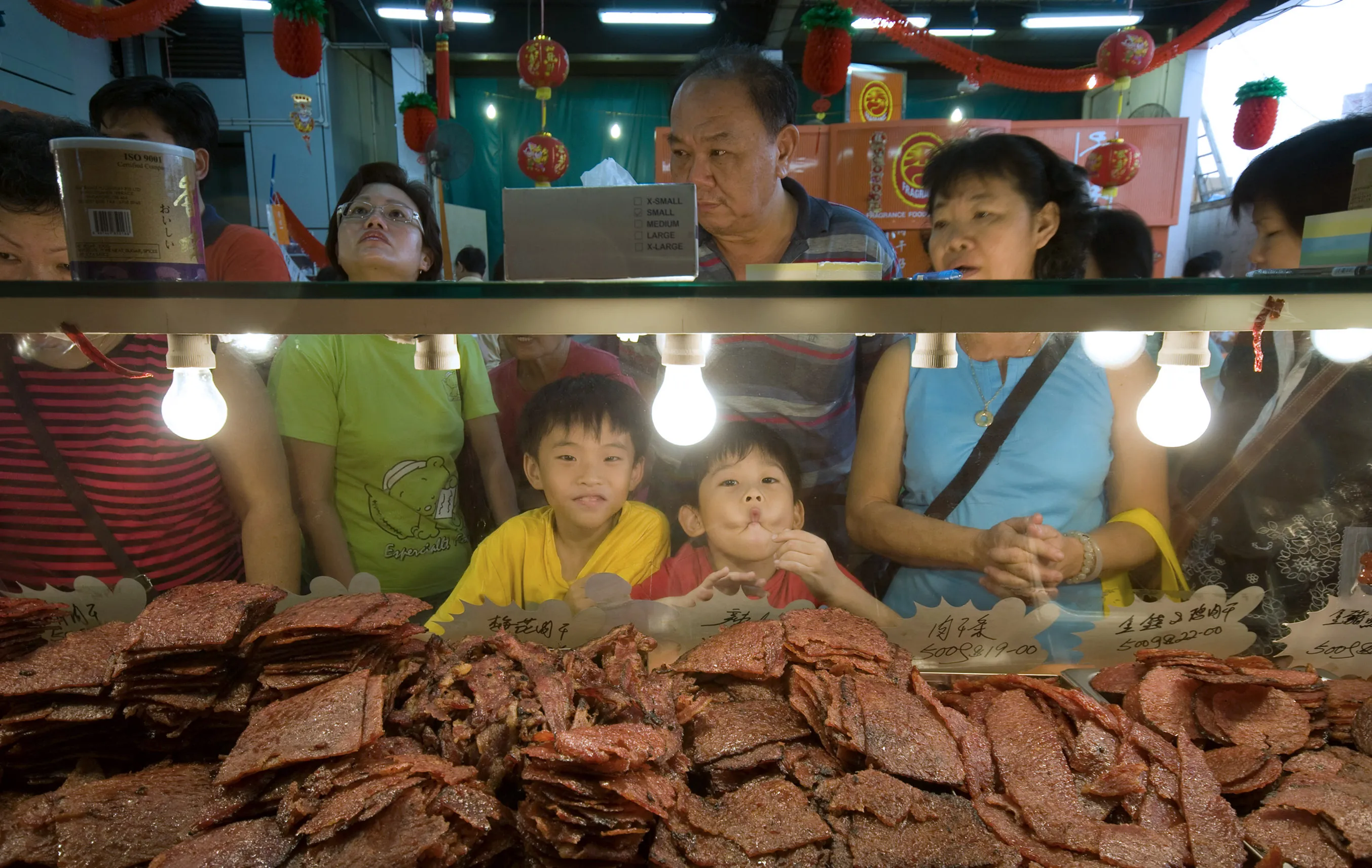 Two boys making funny faces in front of a 'bak kua', or barbecued meat counter in Singapore. 'Bak Kua' is a popular snack among ethnic Chinese during the Chinese New Year season in Singapore.
