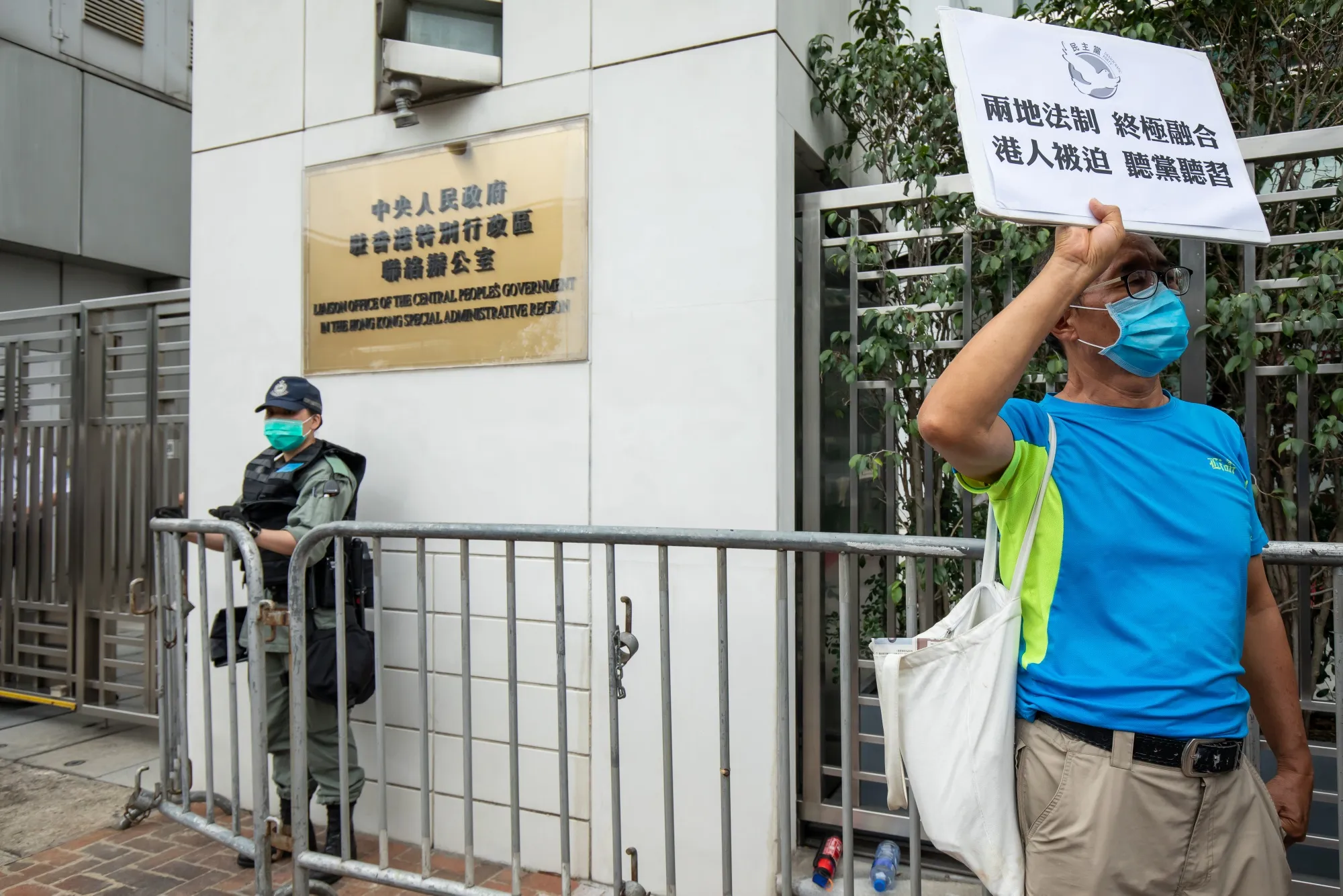 A member of the Democratic Party holds a sign as a police officer stands guard during a protest in front of the Liaison Office of the Central People's Government in Hong Kong on May 22.