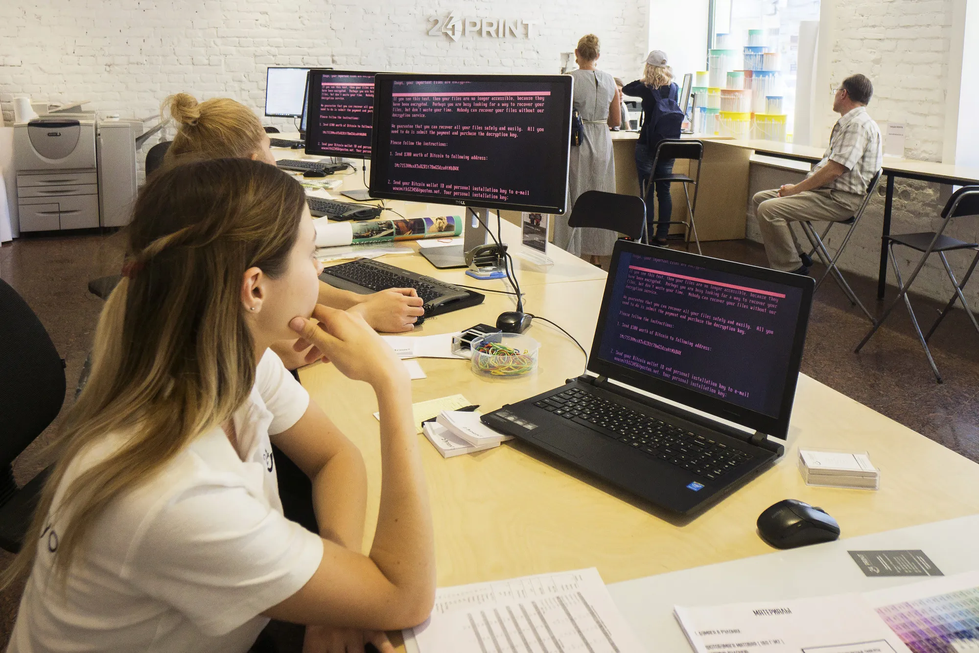 Employees read a ransomware demand on company computers.