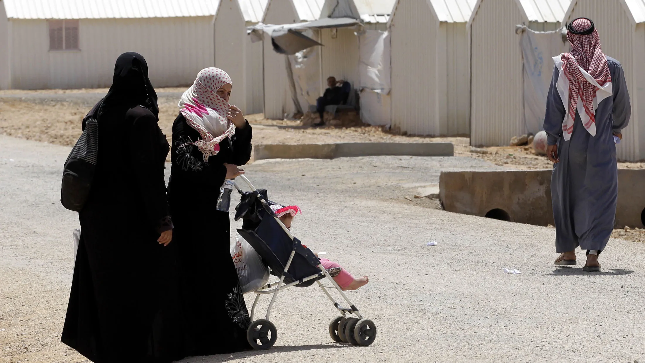 Syrian refugees, who fled the deadly conflict in their country, walk past pre-fabricated buildings at Azraq refugee camp on April 28, 2015 in Jordan, some 100 kilometres (60 miles) east of Amman.

