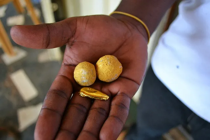 A gold trader displays balls of unrefined gold with a piece of refined gold in Dunkwa-on-Offin, Ghana.