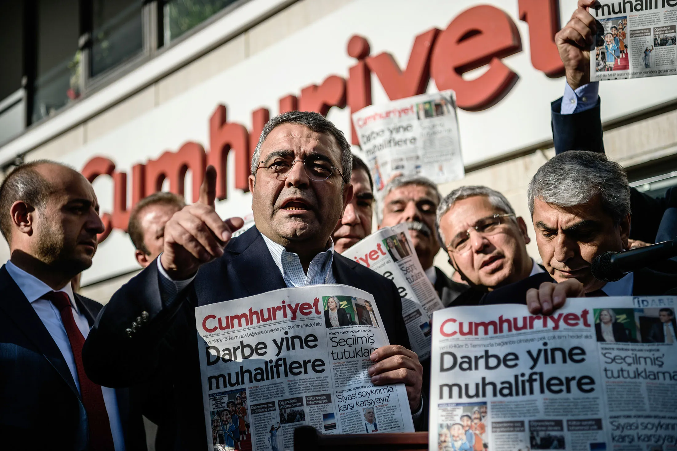 Opposition member of parliament Sezgin Tanrikulu gestures as politicians hold copies of Cumhuriyet newspaper in front of the newspaper's headquarters
