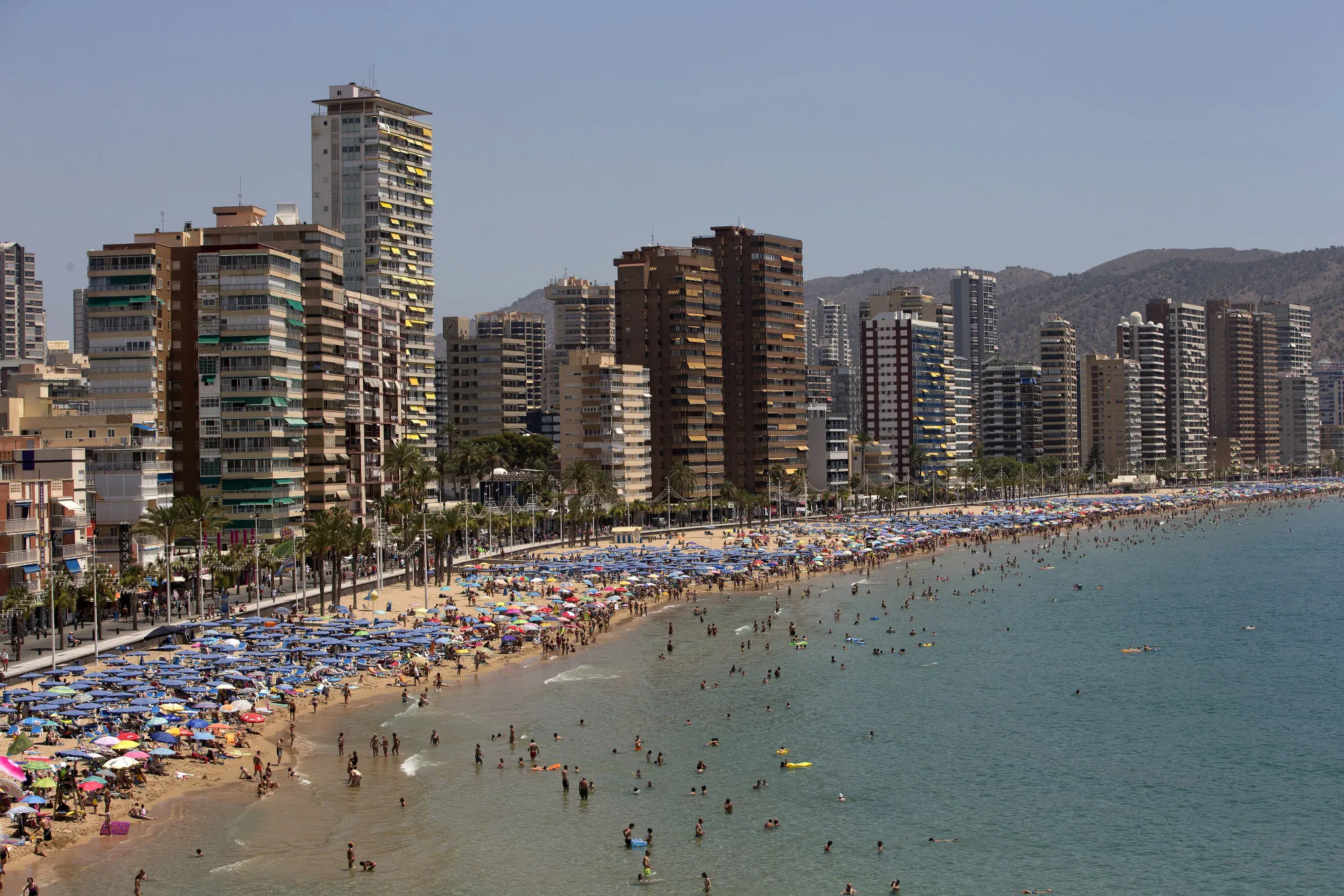 Apartment blocks stand along the waterfront behind a beach packed with holidaymakers in Benidorm, Spain, July 2016.