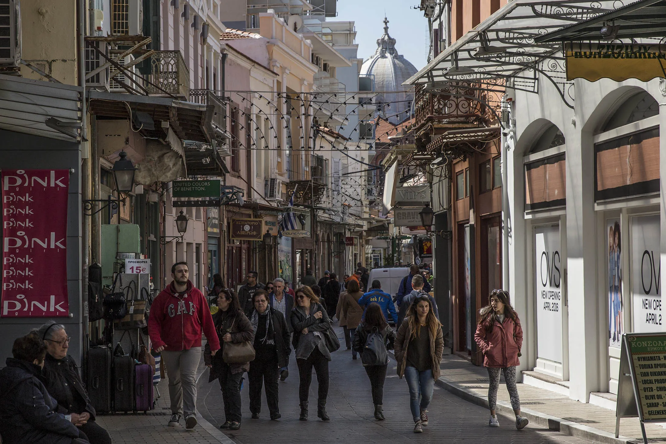 Shoppers walk down a high street in Mytilene, Greece.
