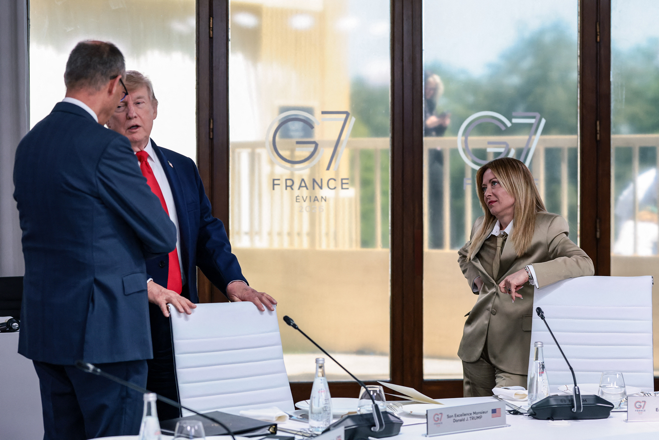 US President Donald Trump speaks with Germany's Chancellor Friedrich Merz next to Italy's Prime Minister Giorgia Meloni during a work lunch as part of the G7 summit, in Evian, eastern France, on June 16, 2026. Photographer: Evelyn Hockstein/AFP/Getty Images