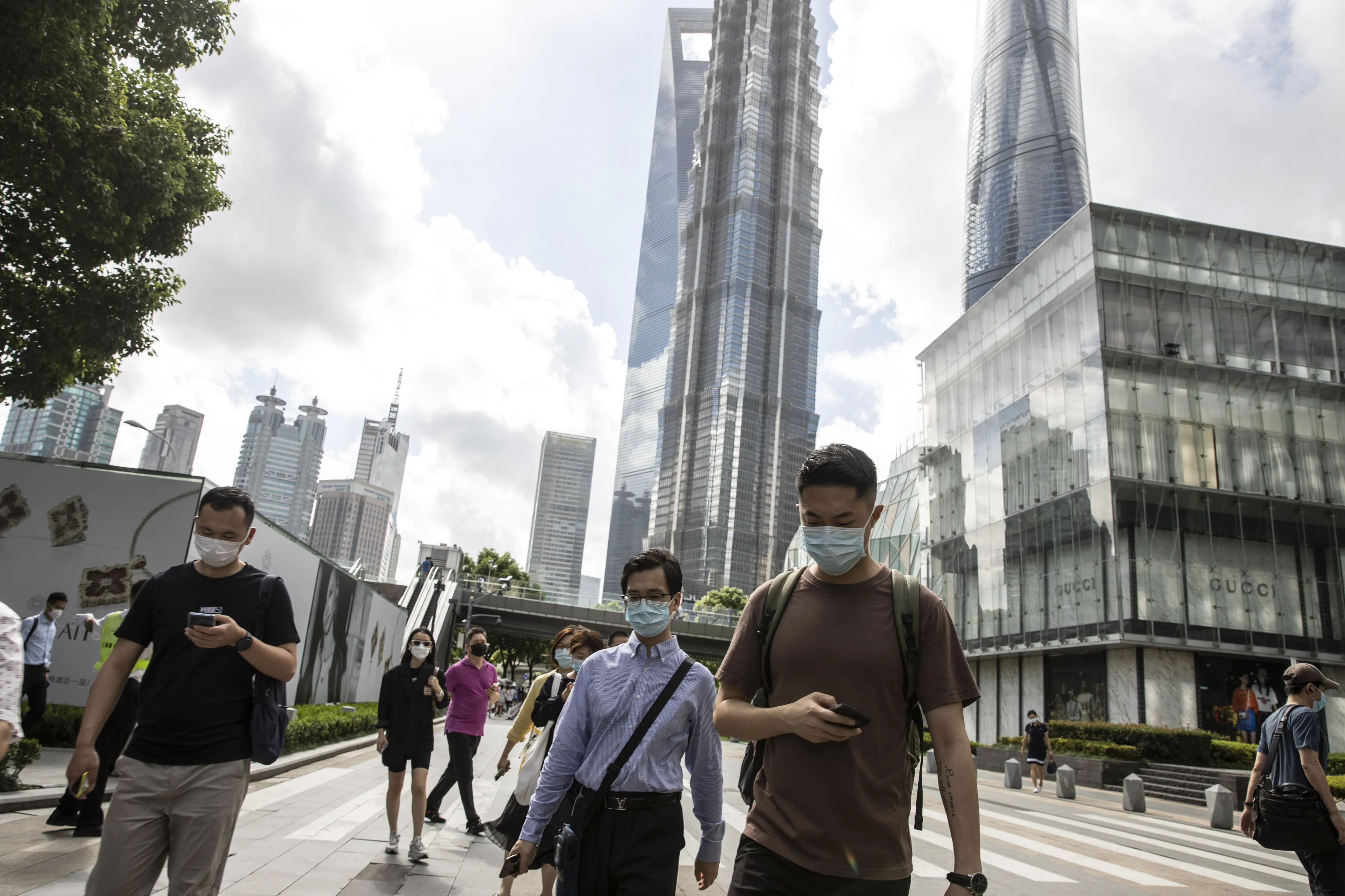 Pedestrians wearing protective masks make their way through the financial district during the morning rush hour in Shanghai, on Aug. 6.