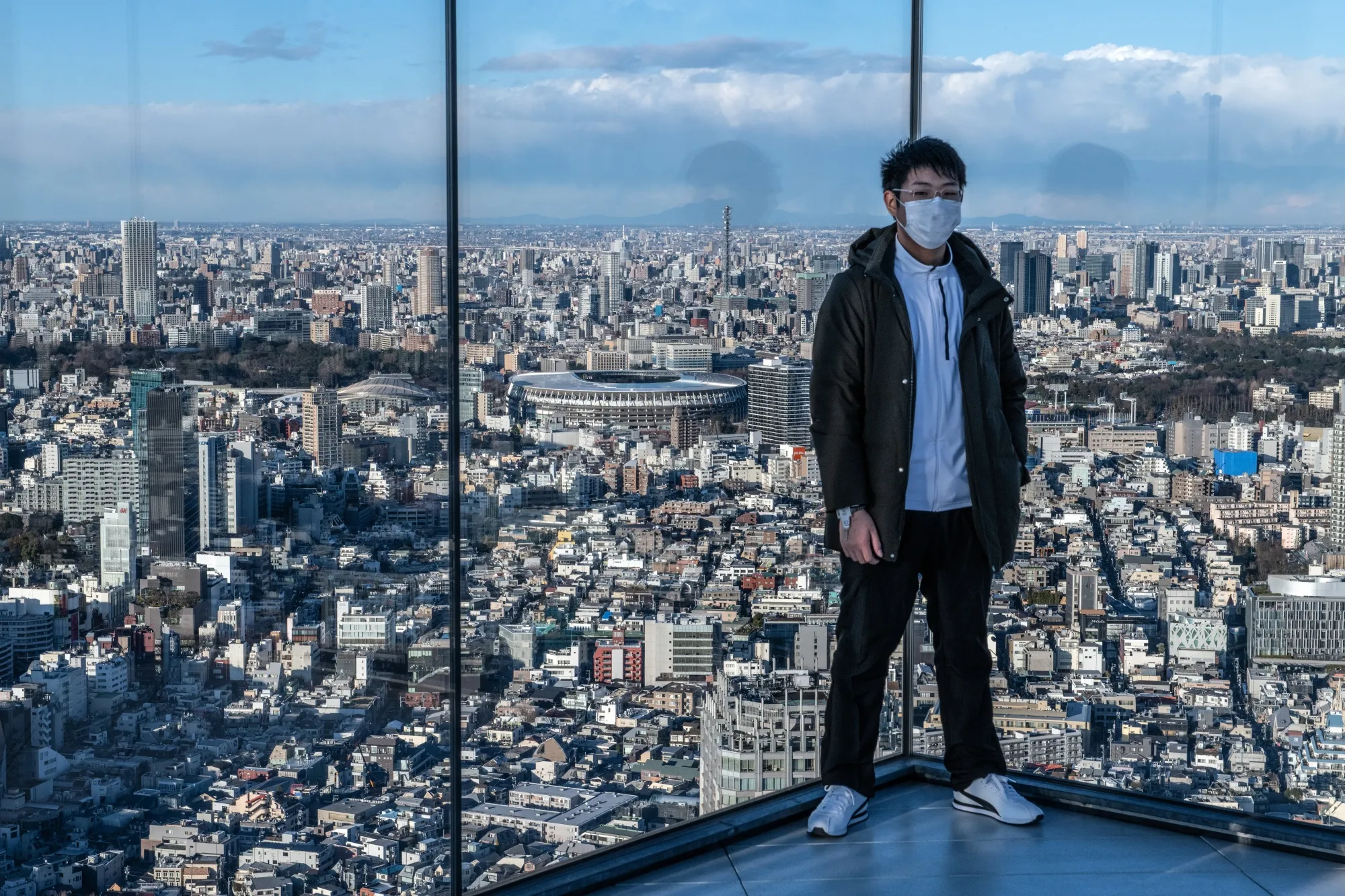 A man in a face mask pose for a photo on the Shibuya Sky observation deck on Feb. 27.