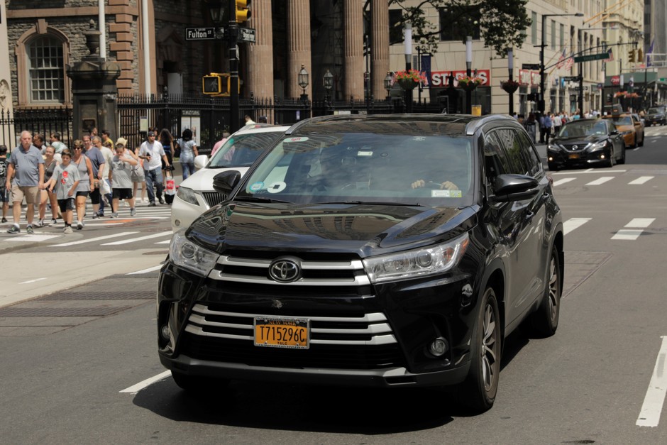 A car with an Uber logo rolls down a New York City street.
