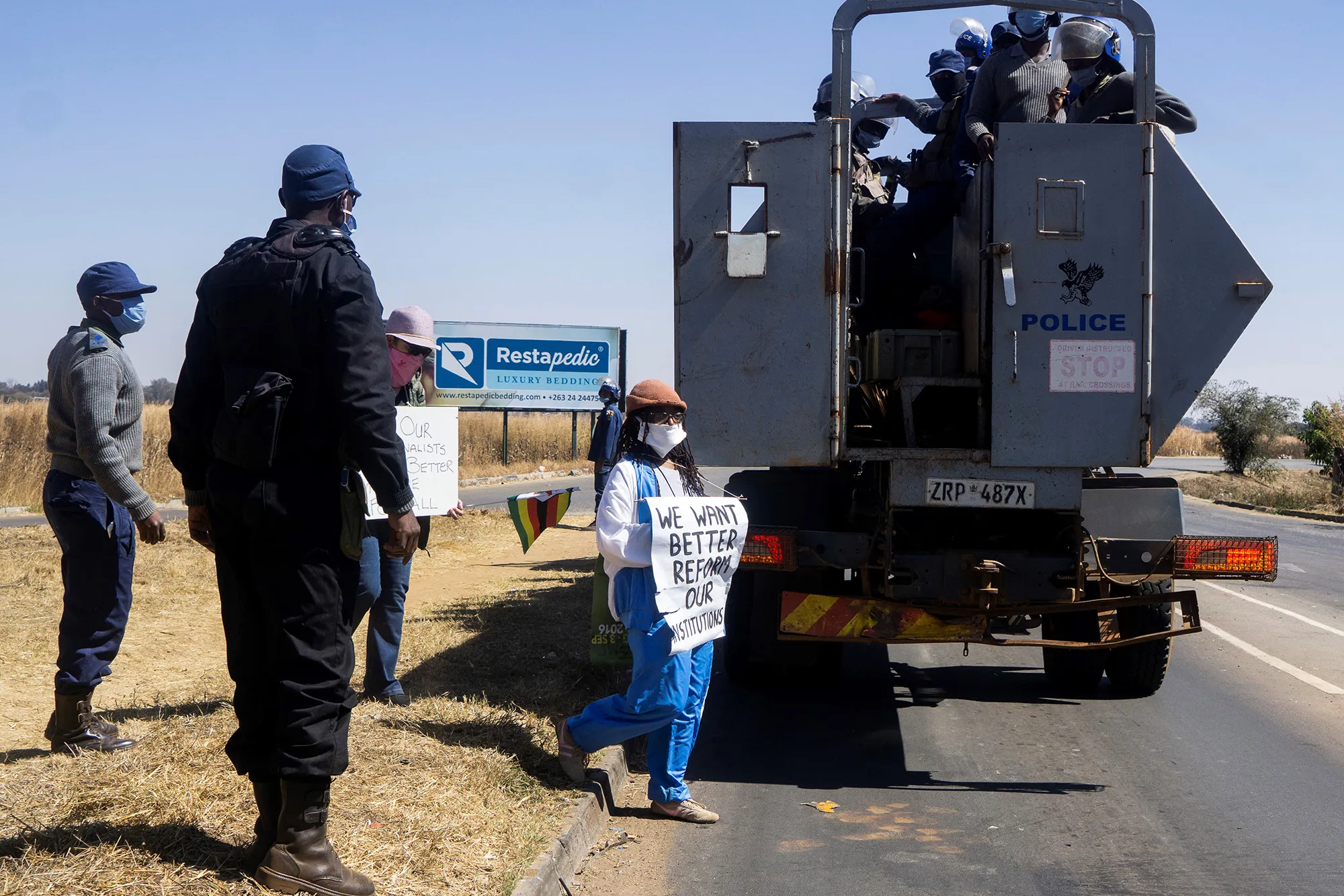 Tsitsi Dangarembga, center, and colleague Julie Barnes hold placards as they are arrested during a protest in Harare&nbsp;on July 31.