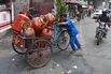 A worker pushes a tricycle loaded with LPG cylinders on a