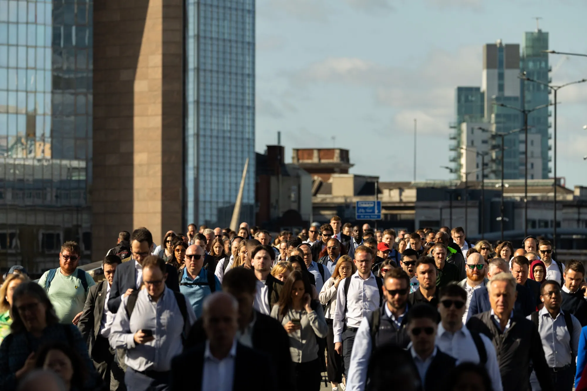 Commuters cross London Bridge, towards the City of London.