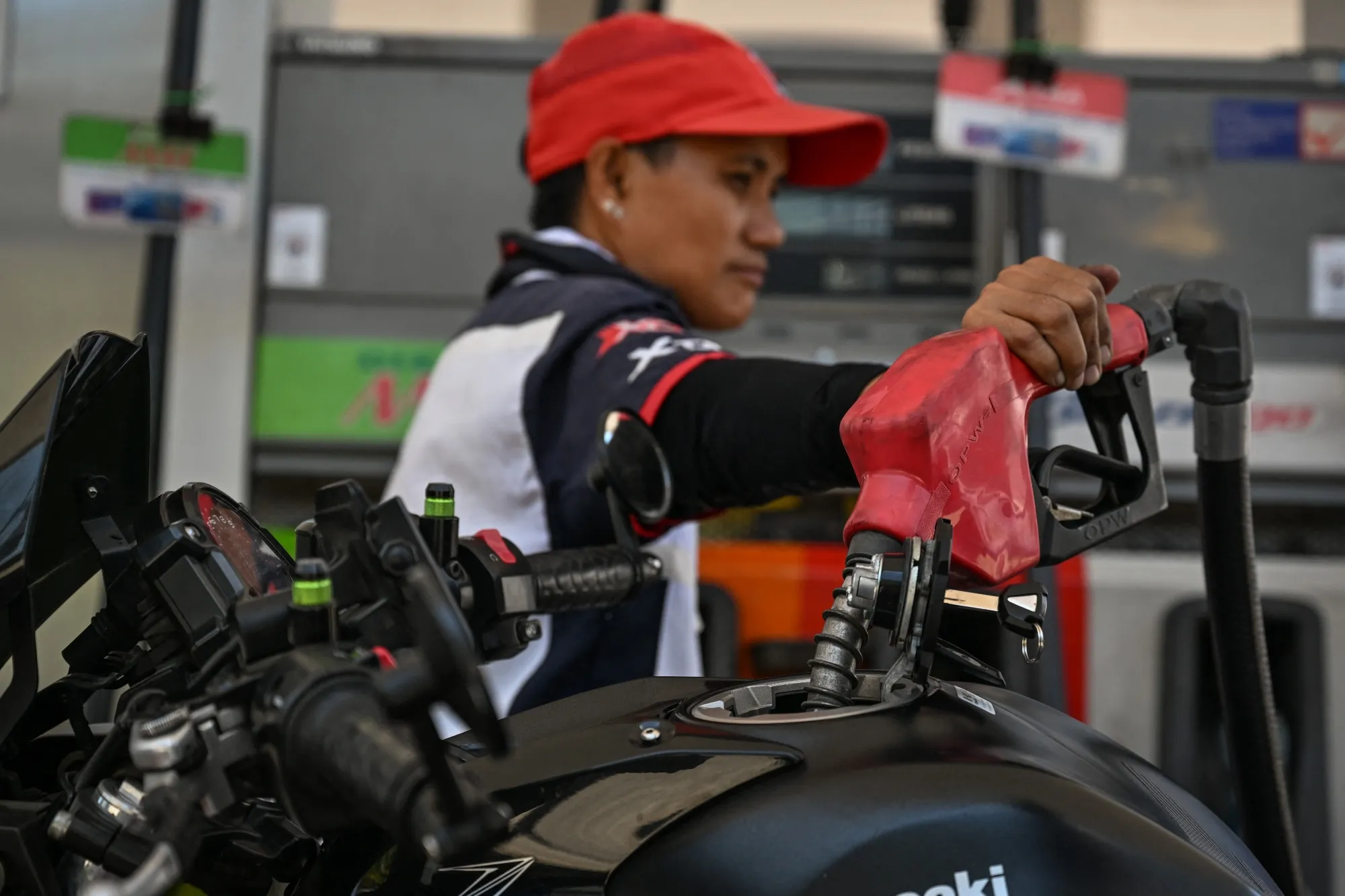 A man refuels the tank of a motorcycle at a petrol station in Manila.
